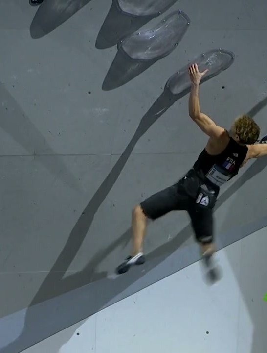 A climber on a grey boulder wall